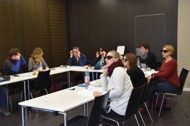 Seminarteilnehmer mit Simulationsbrillen verfolgen den Vortrag von Frau Michels